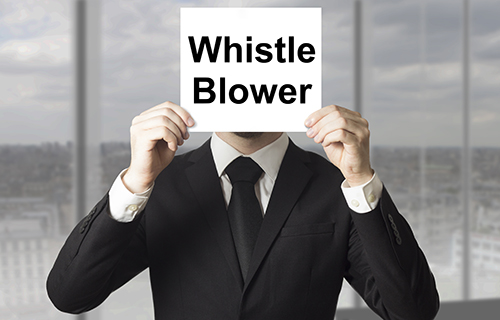 Business man holding a sign in front of his face that says whistle blower