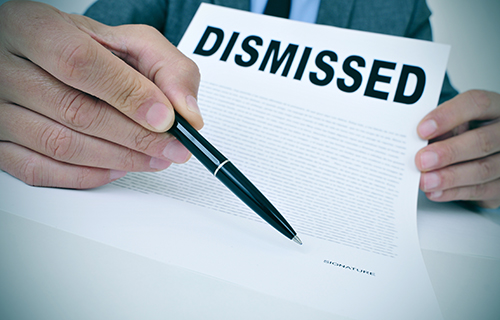 Businessman holding a pen to a paper that says dismissed